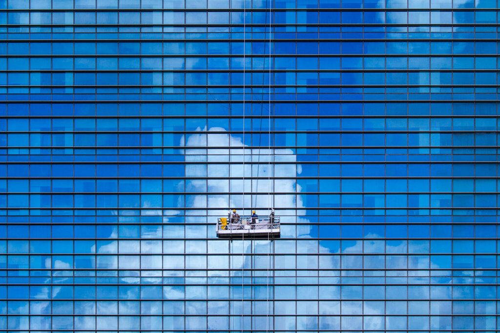 Maintenance vendors servicing a commercial building facade as part of facilities management and building operations oversight.